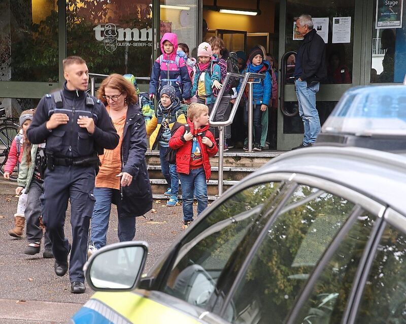 Die Polizei führt die Kinder aus dem Schulgebäude.