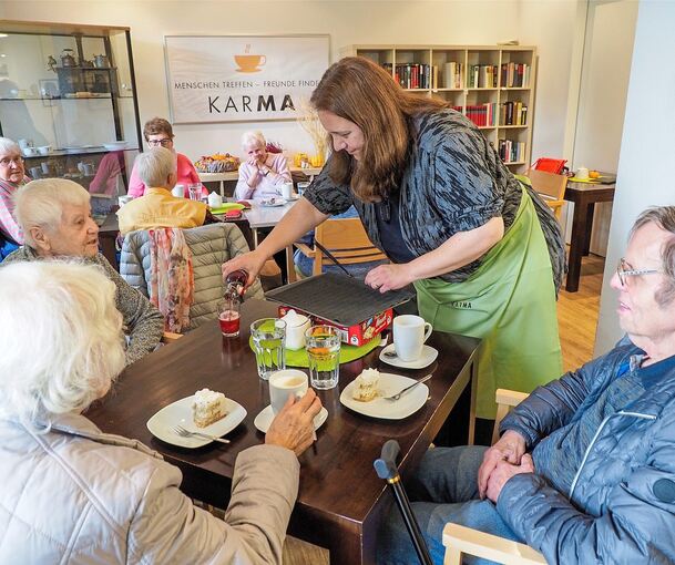 Sandra Süß arbeitet im Café KarMa und serviert Kuchen und Getränke. Im Hintergrund wird Rummy Cup gespielt. Foto: Holm Wolschendorf