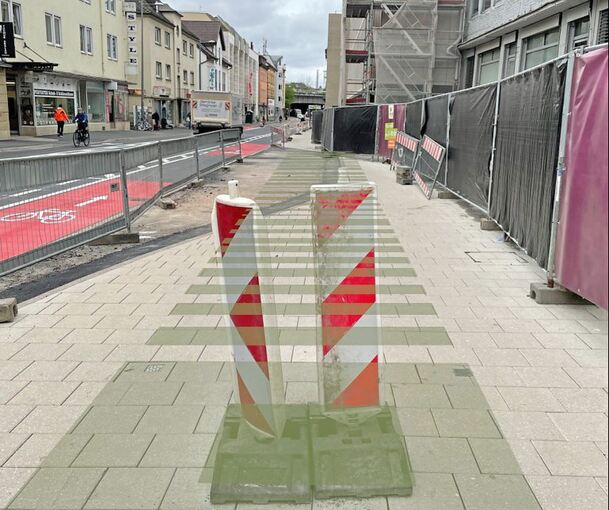 Ein bearbeitetes Foto: Weil man nur Pflastersteine sieht, hat die Stadt auf dem Bild grau markiert, wo unterirdisch die neuen Pflanzbeete sind. Der erste Baum wird dort gepflanzt, wo die weiß-roten Baken stehen.