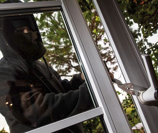 Mit einem Brecheisen wird eine Glastür aufgehebelt.