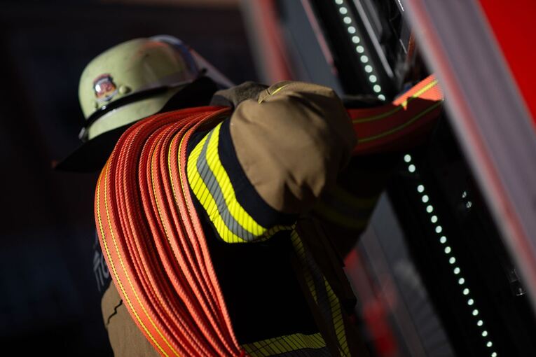 Ein Feuerwehrmann holt einen Schlauch aus einem Einsatzfahrzeug