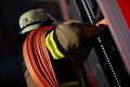 Ein Feuerwehrmann holt einen Schlauch aus einem Einsatzfahrzeug Ein Feuerwehrmann holt einen Schlauch aus einem Einsatzfahrzeug