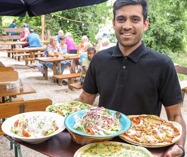 Zeen Azam bringt ein Tablett voller Speisen zu den Gästen.