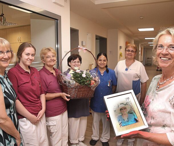 Mit einem Präsentkorb dankte Freia Geer (rechts) dem Team im zweiten Obergeschoss für die Pflege ihrer Mutter Anita Geer, die als Foto dabei ist. Links im Bild Hausdirektorin Elke Eckert.