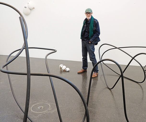 Spannende Kurven: Hans Hemmert in seiner Ausstellung – vorne der räumliche Schriftzug, hinten ein paar seiner Geister.