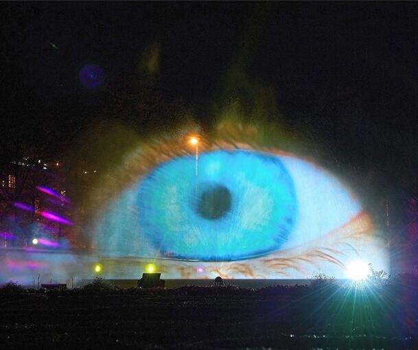 Auf eine Leinwand aus Wasser werden ein Auge und andere Bilder projiziert.