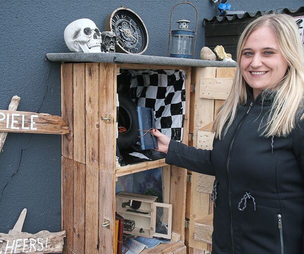 Michaela Veigel mit den Materialien für ihre Escape-Touren: Neben einem Rätselbuch sind auch kuriose Gegenstände dabei - und häufig ein edler Tropfen.