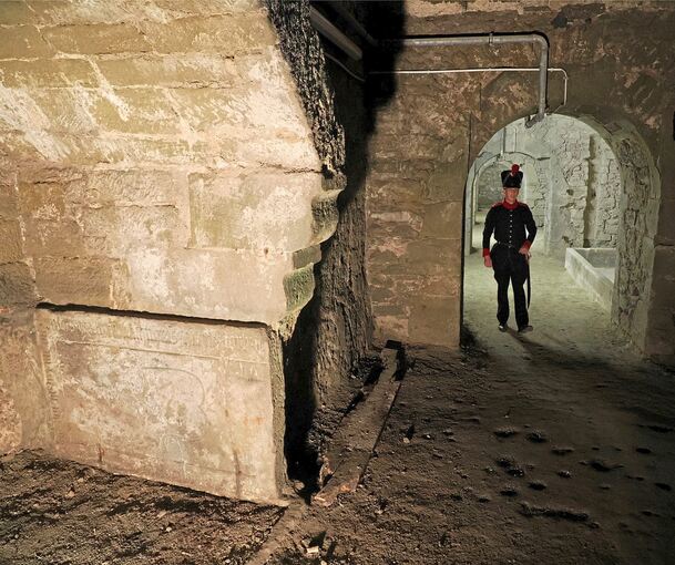 Eine der beiden Grabplatten (vorne links), die in der Dunkelheit der Kasematten ihr Dasein fristeten - bis sie jetzt entziffert wurden. Im Hintergrund Markus Hubel als Torwachen-Offizier Friedrich Wilhelm Beyhl.