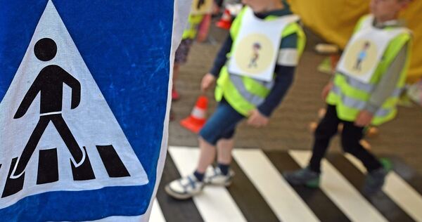 Kinder gehen über einen Zebrastreifen.