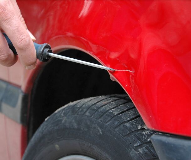 Der Lack eines Autos wird zerkratzt. Der Lack eines Autos wird zerkratzt.