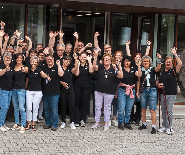 Ein Bildausschnitt zeigt die Orchester der Harmonika-Gemeinschaft. Sie heben alle ihre Hände.
