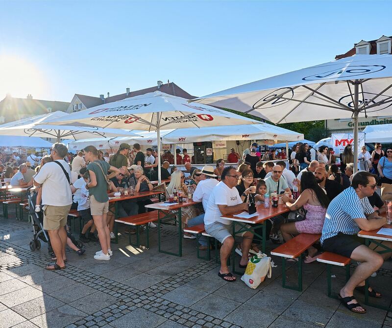 Gut gelaunte Gäste auf dem Marktplatz unterm Schirm.