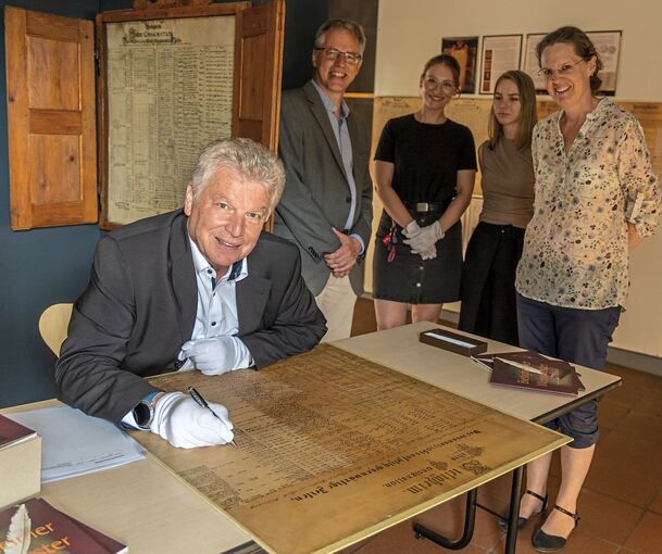 Oberbürgermeister Jürgen Kessing von Bietigheim-Bissingen schreibt in das Weinregister rein, hinter ihm stehen vier Mitarbeiter.