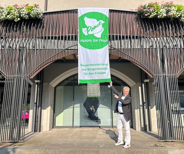 Oberbürgermeister Jürgen Kessing mit der Flagge der Bürgermeister für den Frieden.