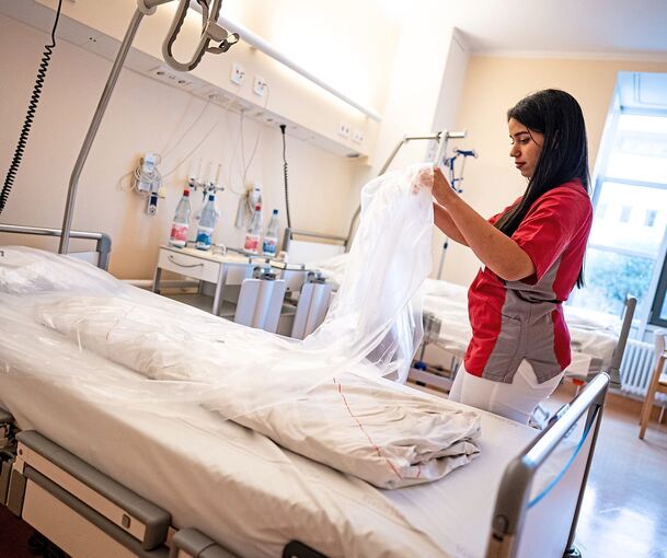 Eine Pflegerin bereitet das Bett für den nächsten Patienten in einer Klinik vor.