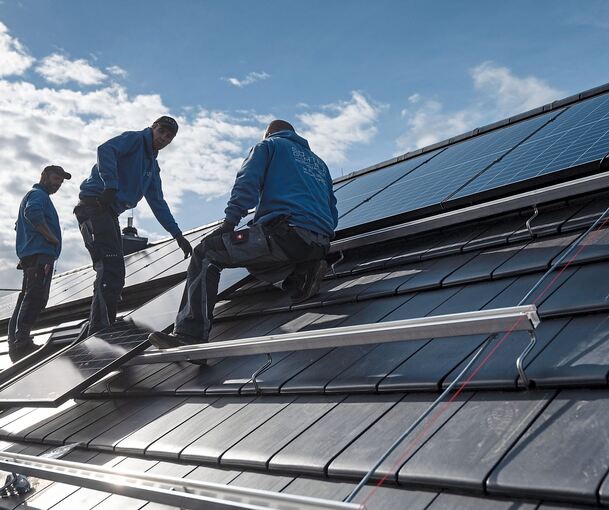 Handwerker bringen eine PV-Anlage auf einem Hausdach an.