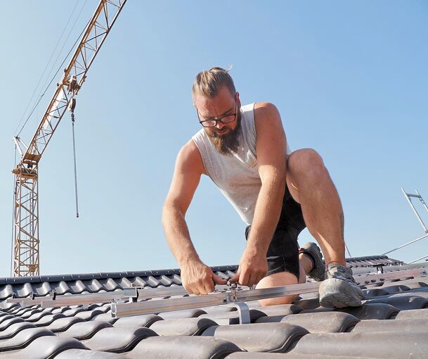 Zimmerer Philipp Herbst montiert die Halterung für ein Solarmodul. Noch ist es früh am Morgen und relativ kühl.
