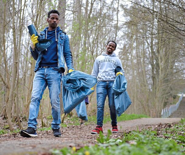 Zwei Asylbewerber sammeln Müll in einem Waldstück. Der Freiberger Bürgermeister Jan Hambach möchte verpflichtende Arbeitseinsätze einführen.