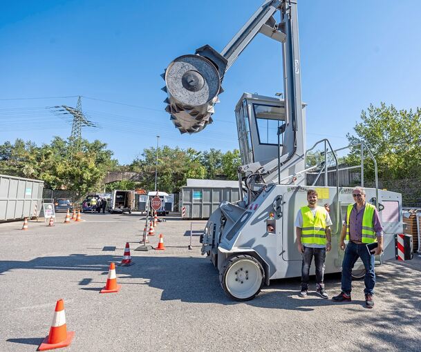 In ihrem Element:Thomas Menges, der örtliche Betriebsleiter (rechts), und Robin Biesinger von der Kommunikationsabteilung stehen vor dem gigantischen Walzenverdichter, der die Containerinhalte platt macht.