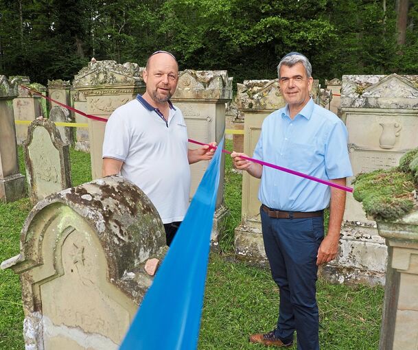 Eine Installation für das Nachfahrentreffen: „Lebenslinien“ heißen die Bänder, die Bürgermeister Alexander Fleig und Michael Volz vom PKC auf dem jüdischen Friedhof in der Hand halten.