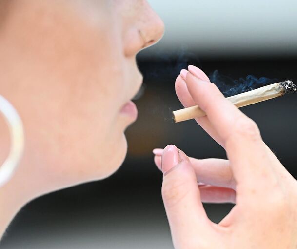 Eine junge Frau raucht einen Joint.