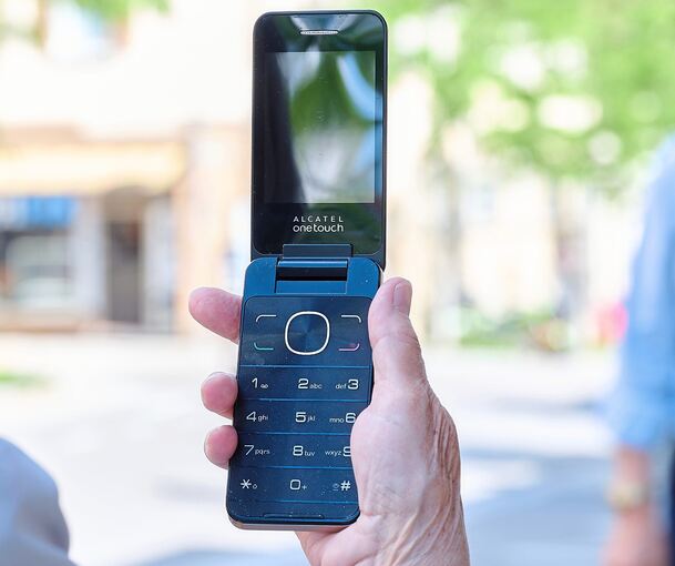 Eine Frau mit ihrem Prepaid-Telefon, das sie mit Guthaben aufladen wollte. Der Frau wurde in einem Ludwigsburger Laden gesagt, das Prepaid-System werde abgeschafft (was falsch ist); stattdessen wurde ihr ein Vertrag angeboten - so wie in dem in diese