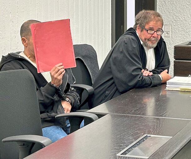 Bild vom ersten Prozesstag: Der Angeklagte verbirgt sein Gesicht. Daneben sein Verteidiger.