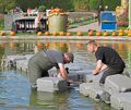 Bevor die Besucher in die magischen Lichteffekte eintauchen, tauchen die Männer in Anglerhosen ins Wasser und installieren die Technik.