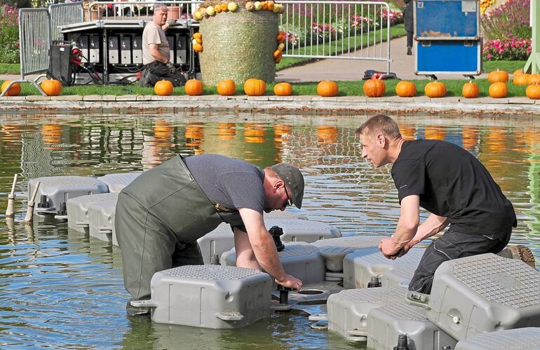 Bevor die Besucher in die magischen Lichteffekte eintauchen, tauchen die Männer in Anglerhosen ins Wasser und installieren die Technik.