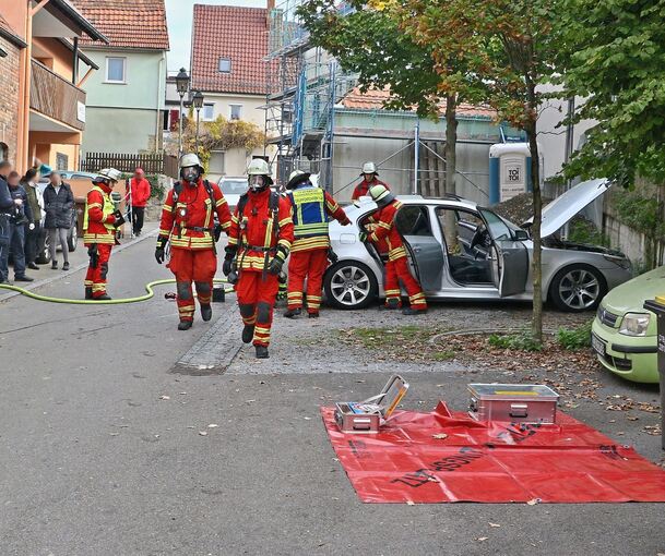 Feuerwehrleute erledigen die Nachlöscharbeiten an dem BMW im Markgröninger Ortskern.