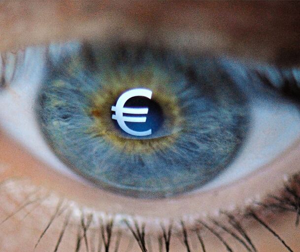 Ein Eurozeichen spiegelt sich in einem Auge: Mittlerweile sind nicht mehr nur Obdachlose oder Bürgergeldempfänger von Schulden betroffen, sondern genauso Ärzte, Architekten und andere Berufsgruppen.