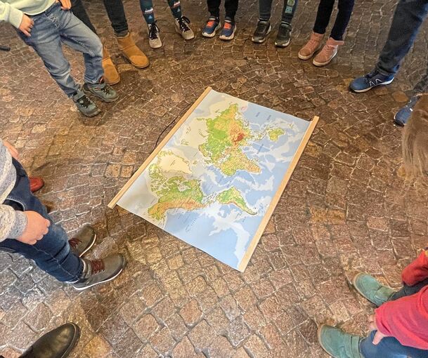 Wo ist Venezuela? Im Kreis stehen die Kinder um eine Landkarte und schauen, wo die Besigheimer Künstlerin später gelebt hat