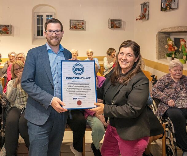 Markgröningens Bürgermeister Jens Hübner und die Leiterin des Begegnungszentrums Graziella Scaricamazza halten die Weltrekord-Urkunde für die längste Rollatorenkette in den Händen.
