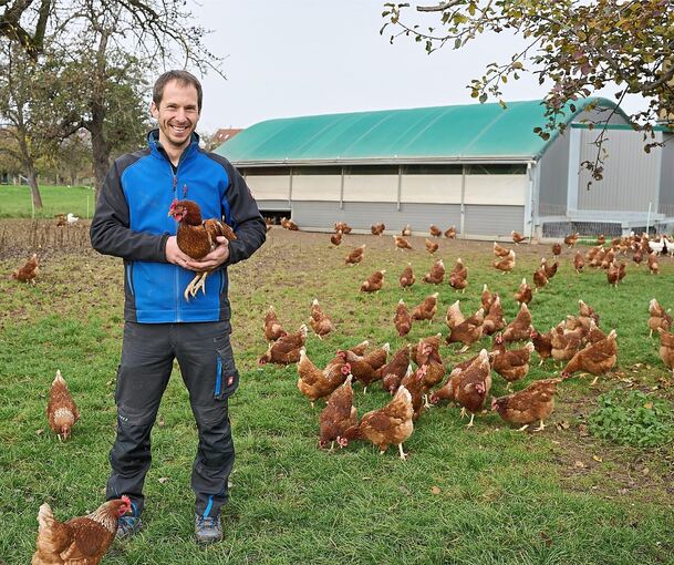 Florian Hirschmann inmitten seiner glücklichen Hühner mit Berta auf dem Arm. In zwei Ställen haben insgesamt 1700 Hühner Platz. Ab zehn Uhr geht‘s raus ins Freie. Noch.