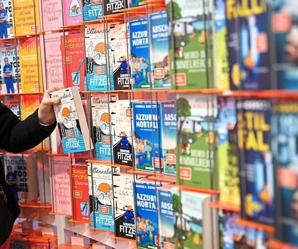 Eine Person nimmt ein Buch aus dem Ladenregal.