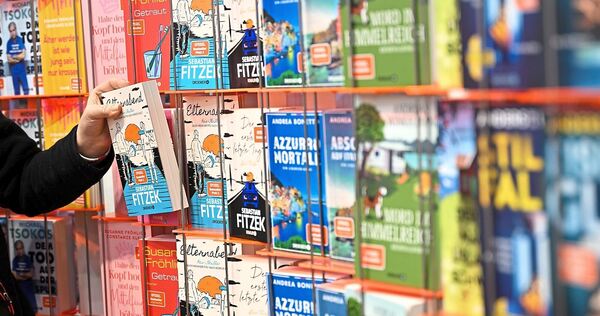 Eine Person nimmt ein Buch aus dem Ladenregal.