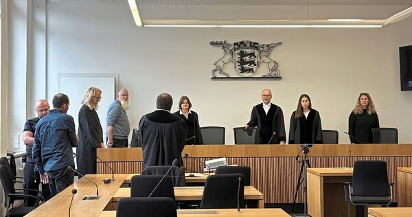 Blick in den Gerichtssaal vor der Urteilsverkündung. Der Angeklagte steht am linken Bildrand mit dem Rücken zur Kamera.