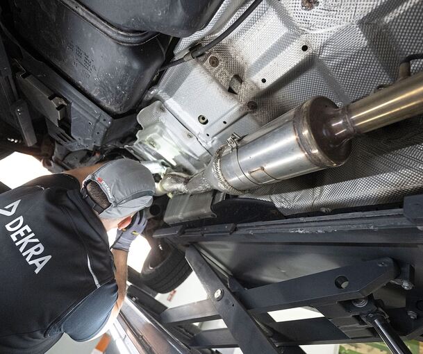 Ein Mitarbeiter der Prüforganisation Dekra untersucht im Rahmen einer Hauptuntersuchung (HU) ein Kraftfahrzeug auf einem Prüfstand.