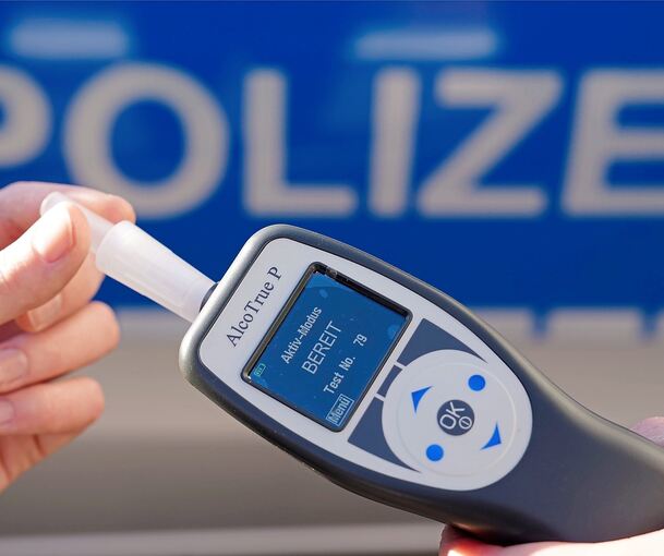 Ein Polizist hält ein Atemalkohol-Messgerät in der Hand.