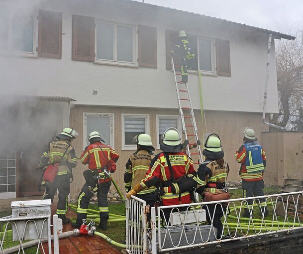 Zum Glück nur eine Übung: Junge Feuerwehrleute retten eine Person aus einem brennenden Haus. Zum Glück nur eine Übung: Junge Feuerwehrleute retten eine Person aus einem brennenden Haus.