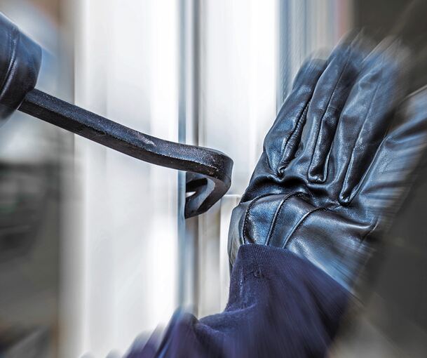Ein Einbrecher hebelt eine Tür auf.