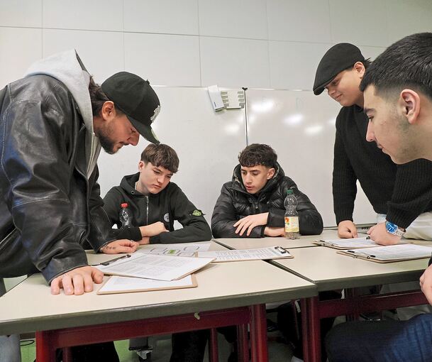 Rapper Morpheuz (links) tüftelt mit Schülern an Texten für einen Schulsong.