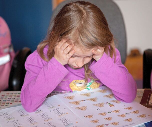 Ein Grundschulkind grübelt über seinen Matheaufgaben.