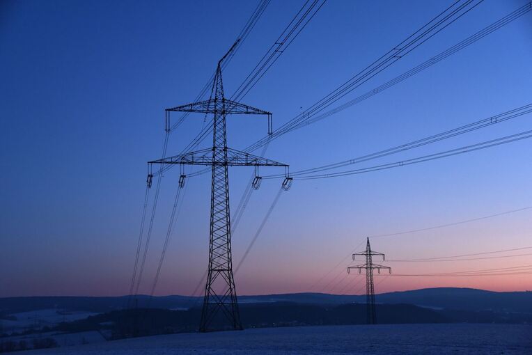 Strommasten in der Morgendämmerung auf einem Feld