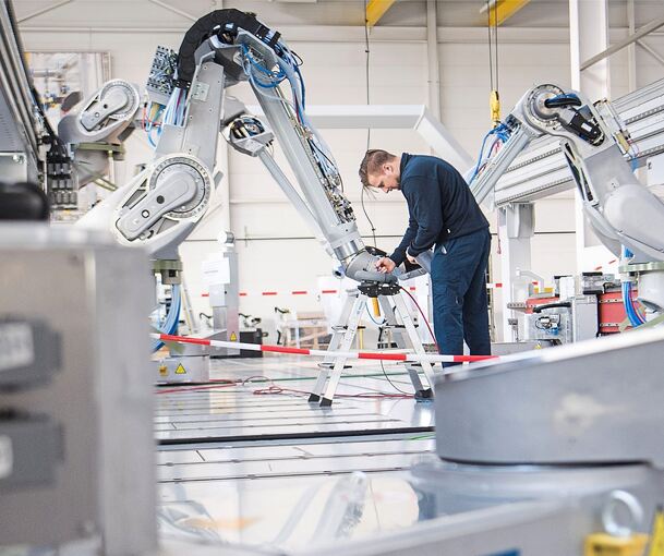 Ein Mitarbeiter testet einen Lackierroboter bei der Dürr AG.