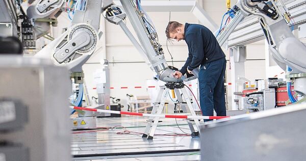 Ein Mitarbeiter testet einen Lackierroboter bei der Dürr AG.