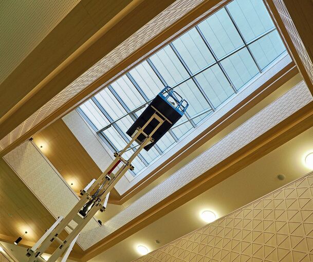 Das Atrium mit seiner raumhohen Öffnung bis zum Dach ist der zentrale Ort der Schule. Mit einer Hebebühne wird eine Lampe angebracht.