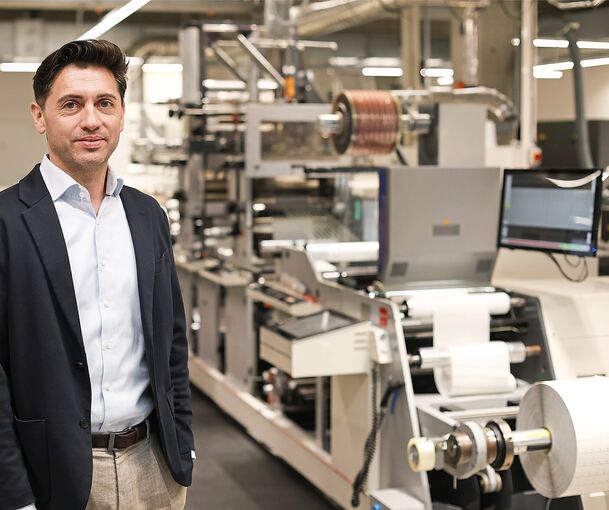 Geschäftsführer Simon Reuter neben einer automatisierten, sogenannten Flexodruckmaschine. Robos-Labels nutzt unterschiedliche Technologien, von analog bis digital - je nach gewünschter Auflösung oder Beständigkeit.