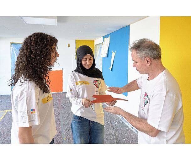 Elena und Shamsa bekommen von Pierre Kölle-Kullmann Unterstützung und Anleitung bei der Wandgestaltung.