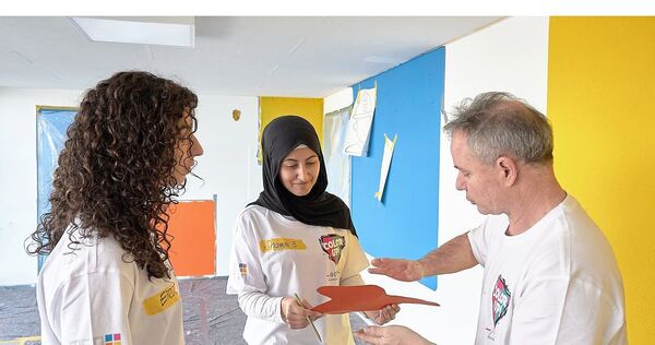 Elena und Shamsa bekommen von Pierre Kölle-Kullmann Unterstützung und Anleitung bei der Wandgestaltung.